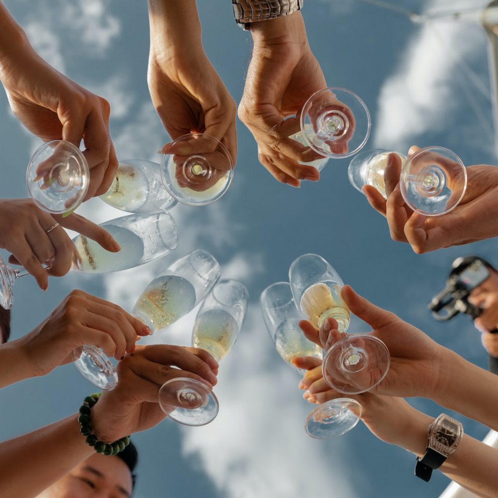 people holding clear glass bottles during daytime